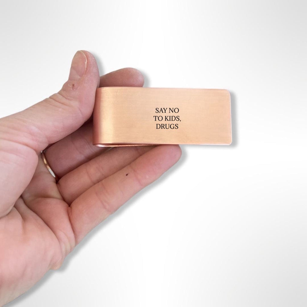 hand holding a copper money clip with black text 