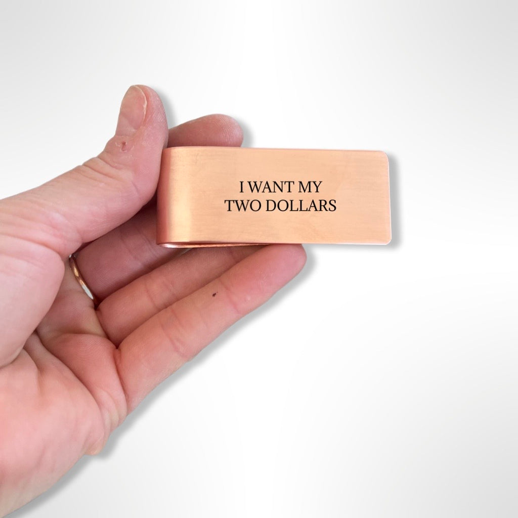 hand holding copper money clip with black text 