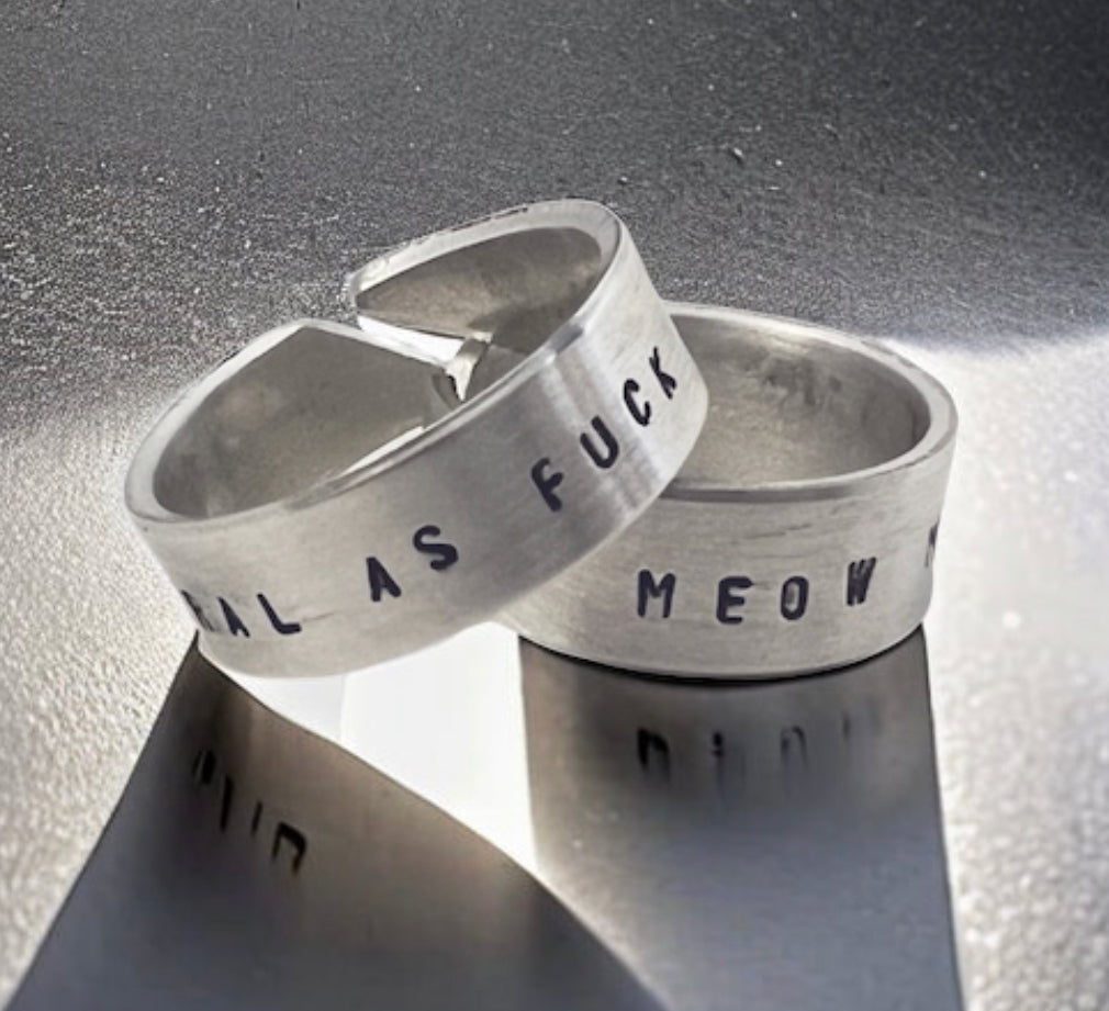 sterling silver cigar band style rings with Feral as Fuck stamped on them in a silver background.
