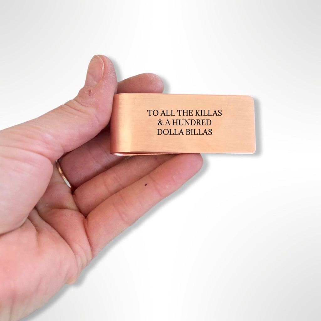 hand holding copper money clip with black text 